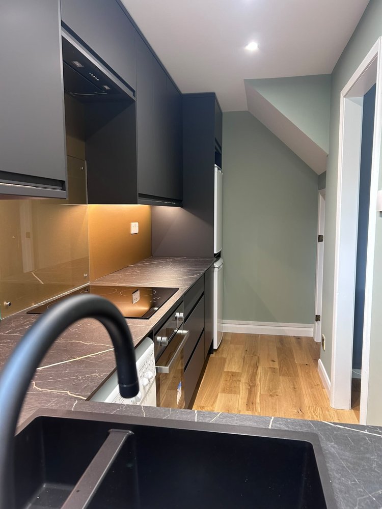 The new kitchen after the refit, with marble-effect worktops and a black sink